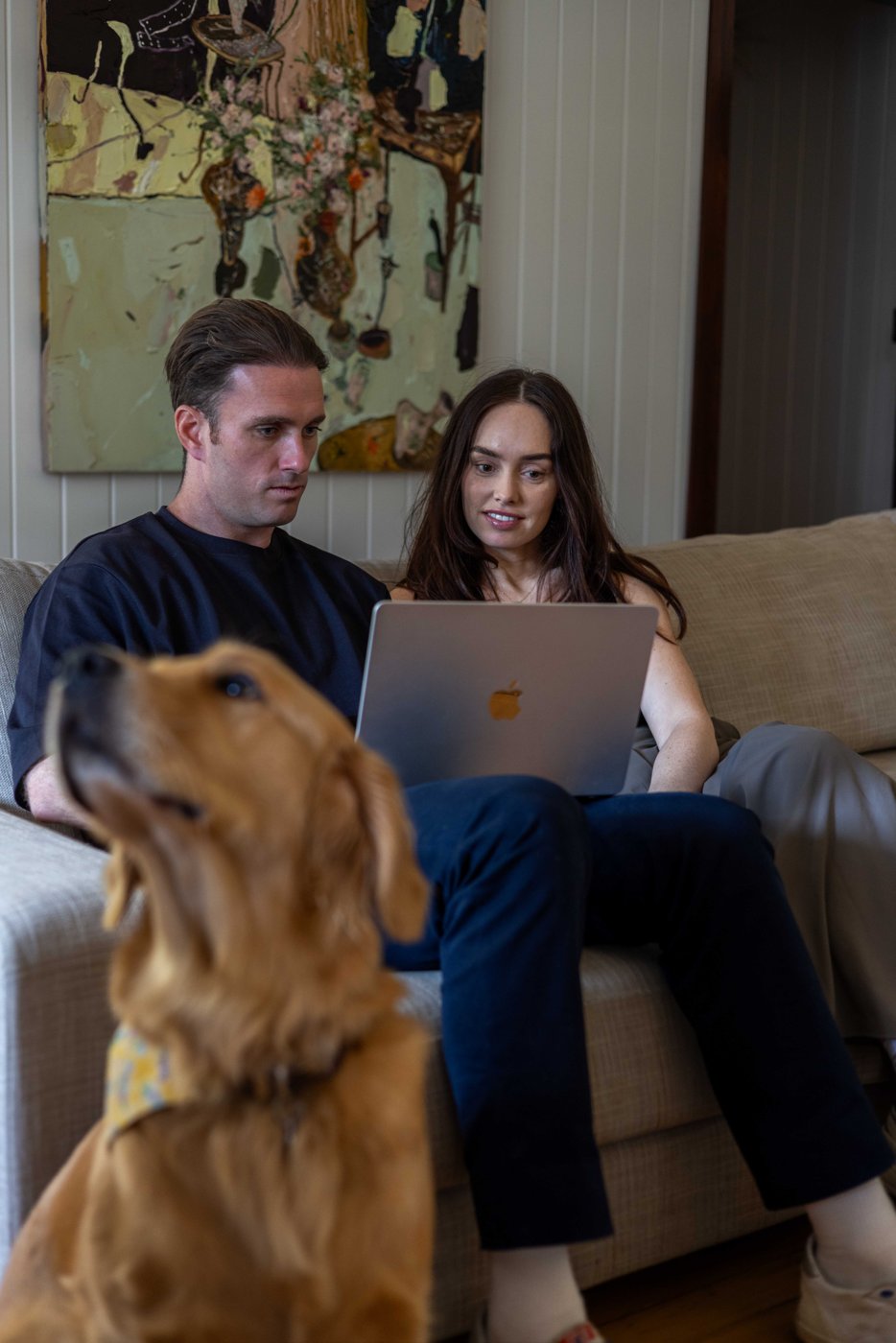 Tim and Maddison from Buywell on a couch with their golden retriever